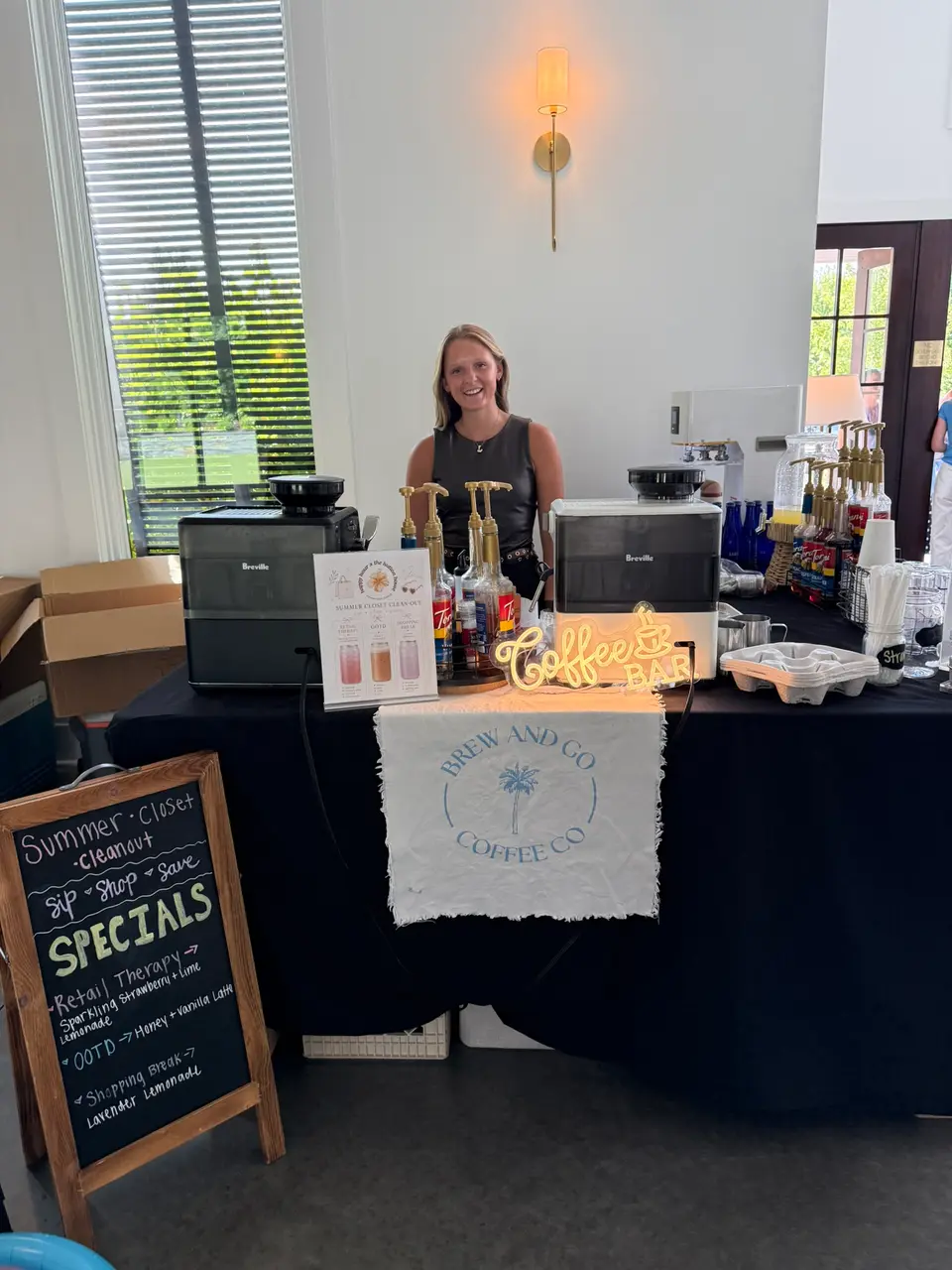 Lexi smiling behind her coffee bar at the Hutton House pop-up